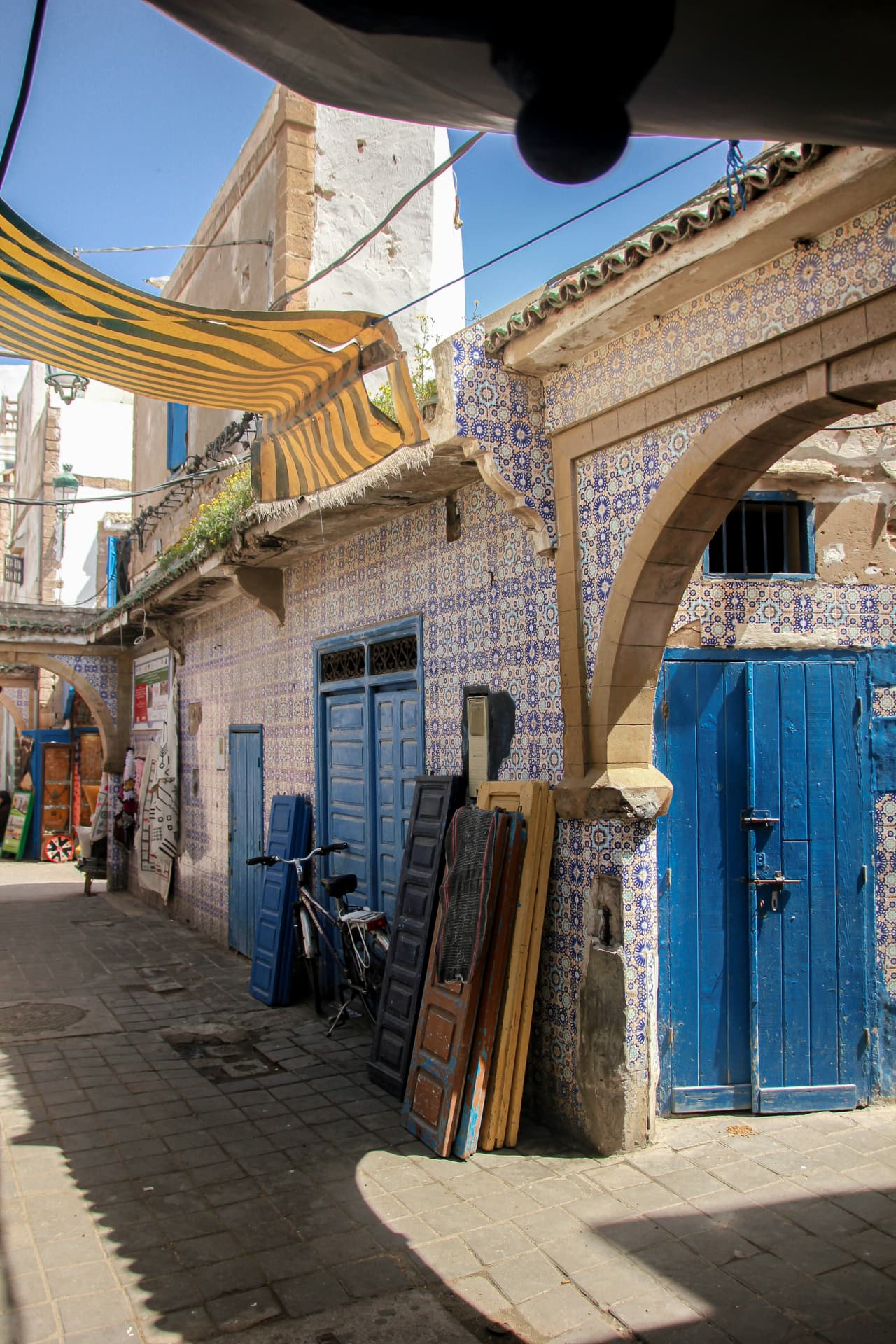 Steeg in de medina met felblauwe deuren en mozaïektegels