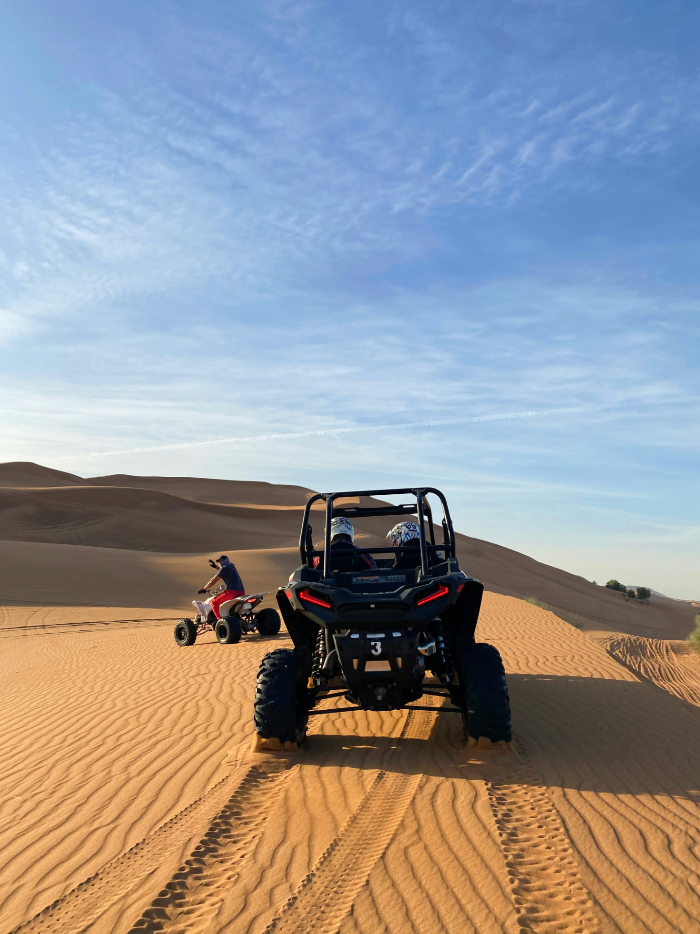 Een buggy en een quad crossen door de zandduinen