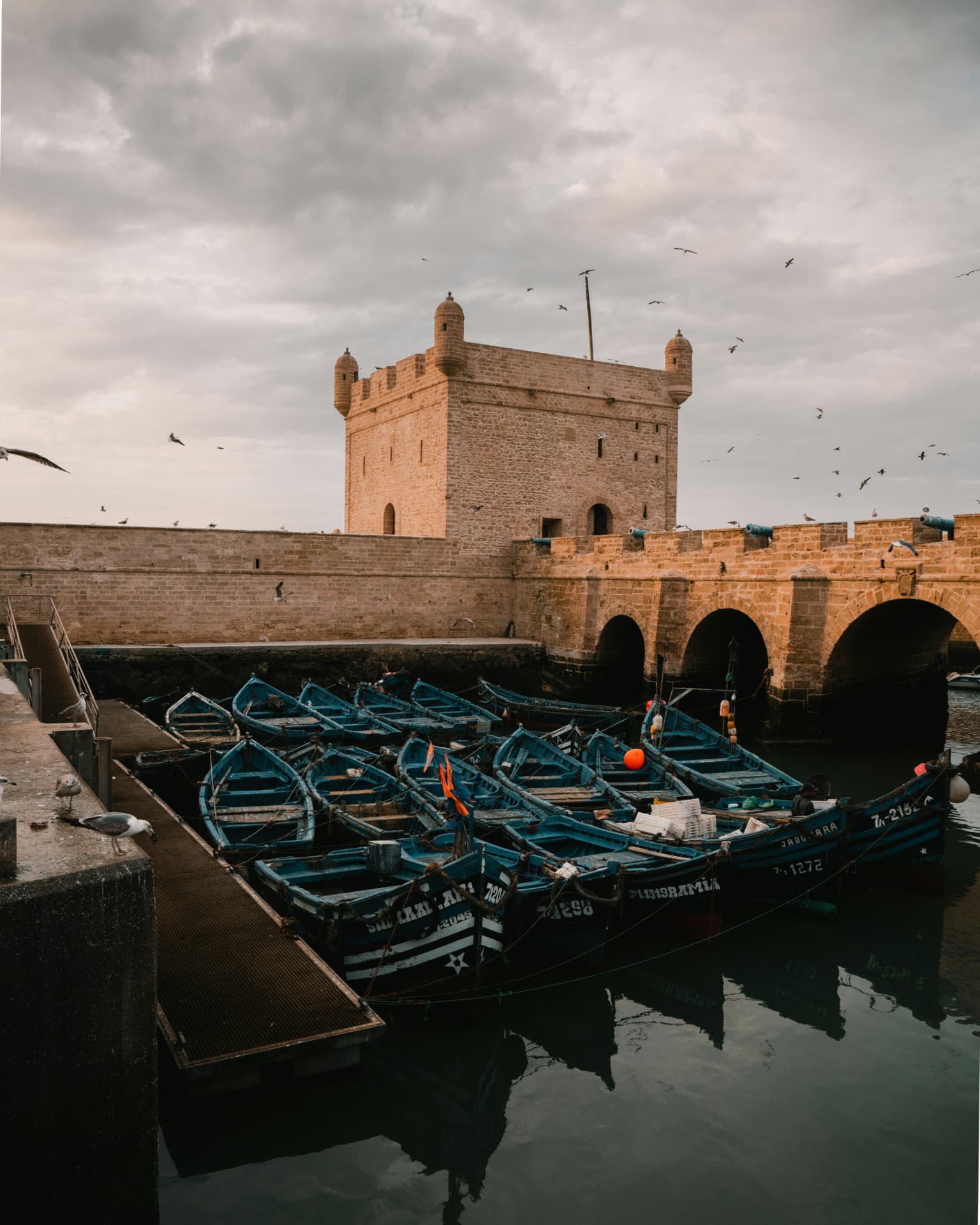 De haven van Essaouira met blauwe vissersboten tussen de stenen muren