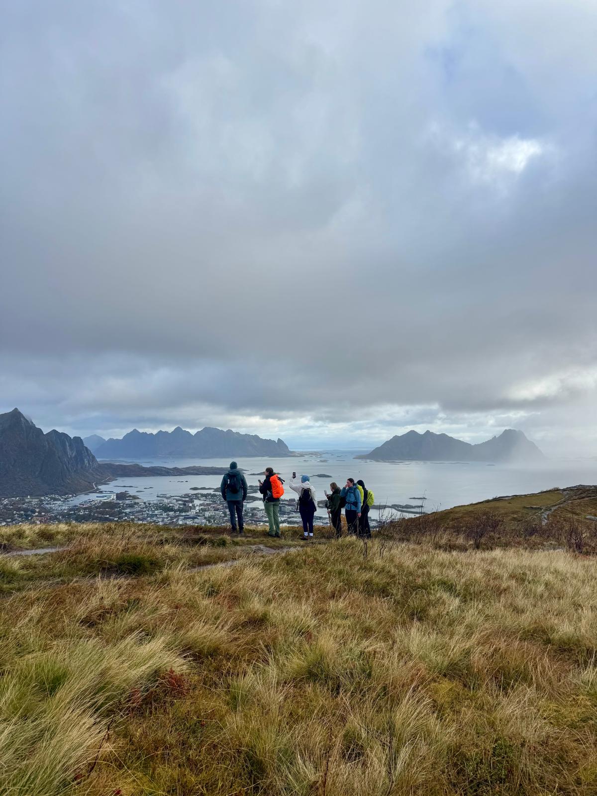 Groep founders kijkt vanaf een berg uit over fjorden en bergtoppen